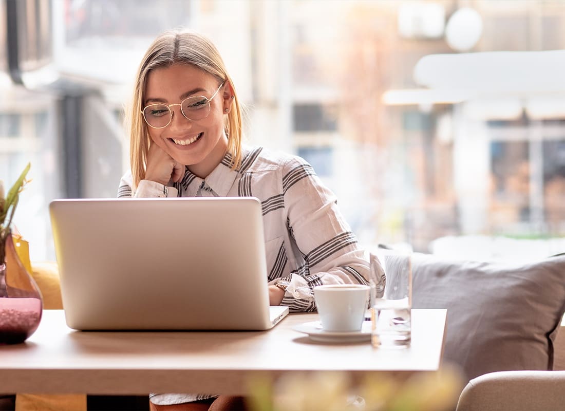 Blog - Portrait of a Young Woman Using Her Laptop for Work at a Cafe